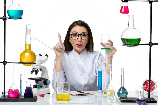 Вид спереди женщина-химик в белом медицинском костюме, держащая фляжку с раствором, белый фон, научный вирус, covid - пандемическая лаборатория