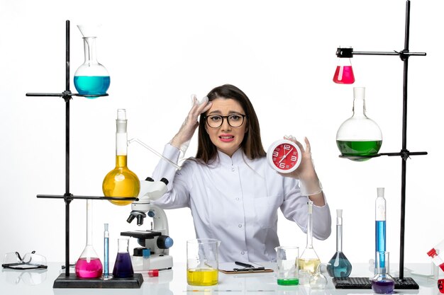 Вид спереди женщина-химик в белом медицинском костюме с красными часами на белом фоне научный вирус covid- пандемическая лаборатория