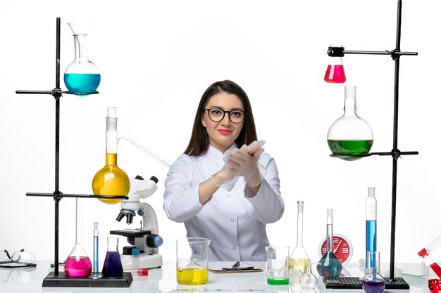 Вид спереди женщина-химик в белом медицинском костюме, просто сидящая с растворами на белом фоне, пандемический вирус науки covid- lab