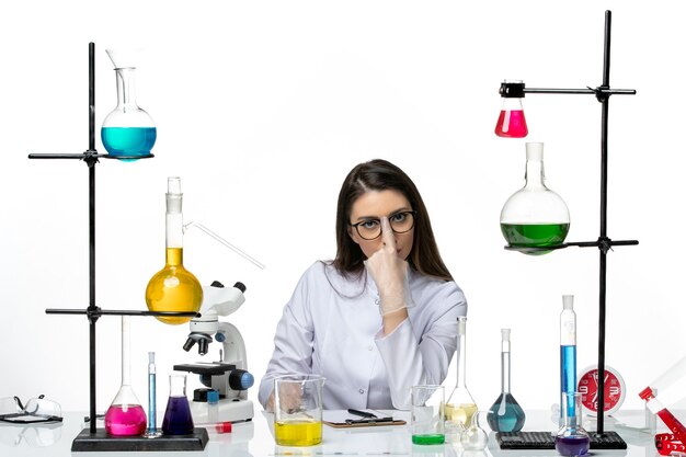 白い背景の科学ウイルスの共同パンデミックラボでの作業の準備をしている白い医療スーツの正面図の女性化学者