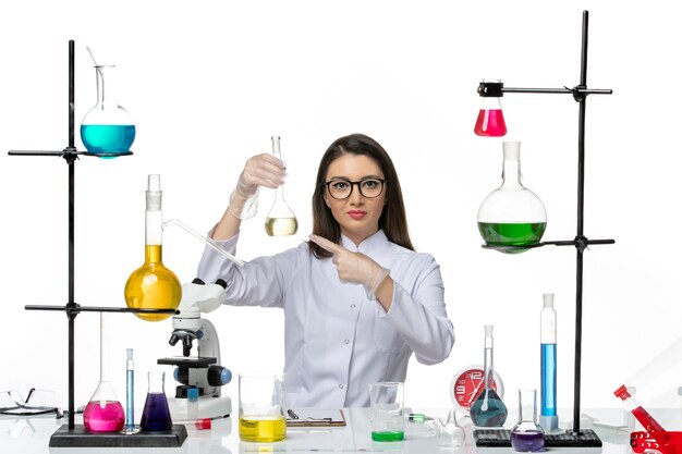 Вид спереди женщина-химик в белом медицинском костюме, работающая с растворами на белом фоне, вирус пандемии лаборатории covid
