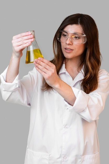 Vista frontale del chimico femminile con occhiali di sicurezza che tengono la provetta