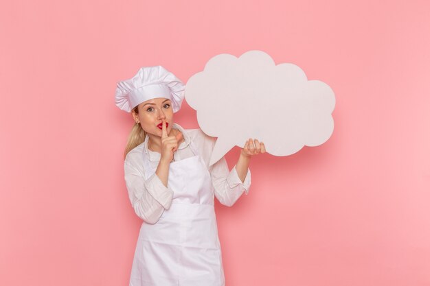 분홍색 벽 요리 작업 주방 요리 음식에 큰 흰색 기호를 들고 흰색 착용에 전면보기 여성 제과