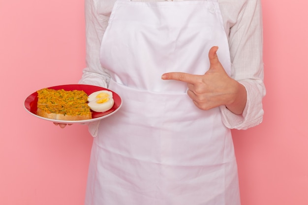 ピンクの壁に食べ物が付いている白い摩耗保持プレートの正面図女性菓子屋料理キッチン料理食べ物