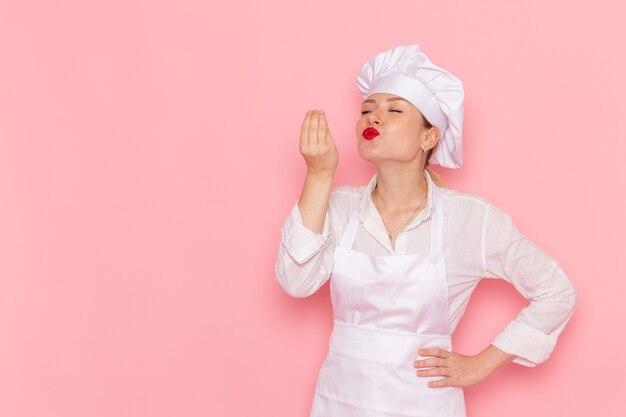 ピンクの壁にポーズをとって白い服を着た正面図の女性菓子屋料理菓子甘いペストリーの仕事