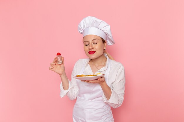 Front view female confectioner in white wear preparing meal on pink wall cook job kitchen cuisine food