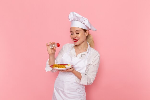 Front view female confectioner in white wear preparing meal on the pink wall cook job kitchen cuisine food