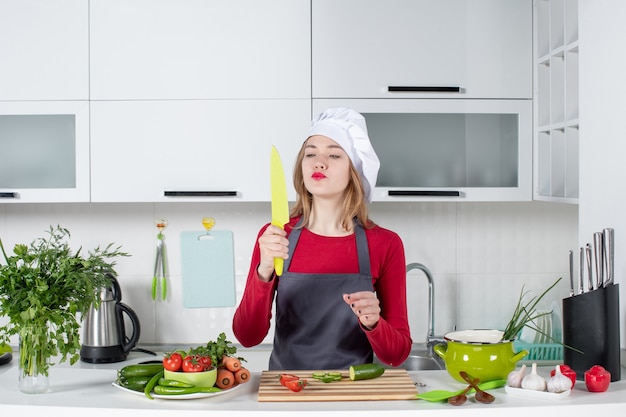 Front view female cook in apron looking at knife in her hand