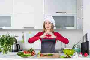 Free photo front view female cook in apron making heart sign