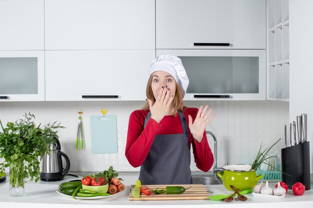 Front view female cook in apron putting hand on her mouth