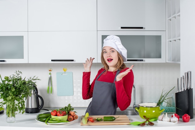 Front view female cook in apron standing behind kitchen table