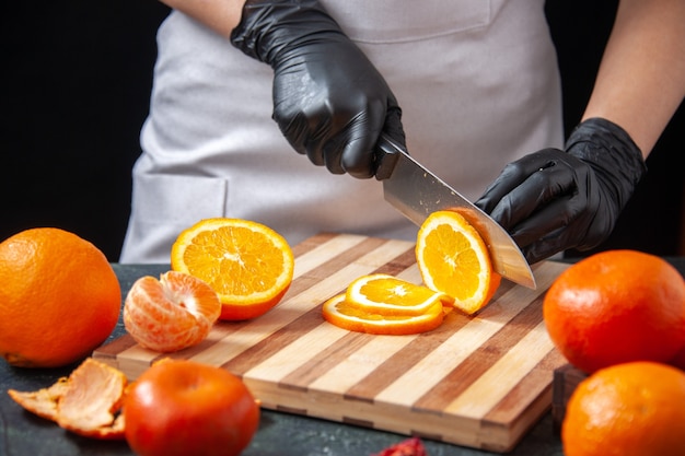 Front view female cook cutting orange on a dark vegetable drink health meal food job fruit diet salad