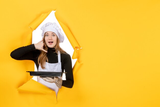 Front view female cook holding black pan with biscuits on yellow emotion sun food photo job cuisine color