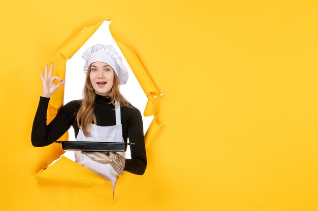 Front view female cook holding black pan with biscuits on yellow emotion sun food photo job kitchen color