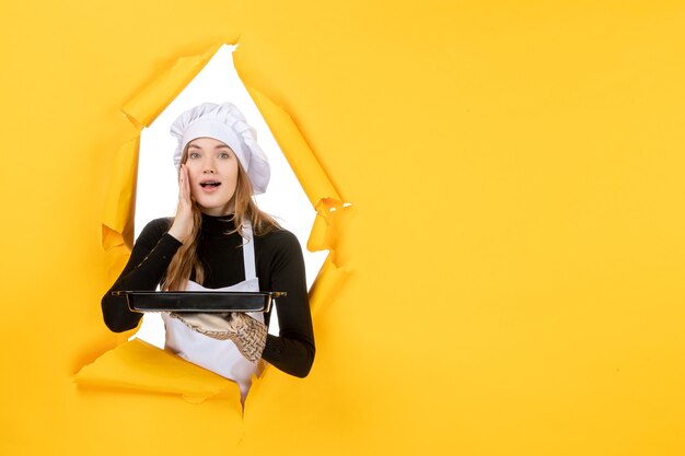 Front view female cook holding black pan on yellow emotion sun food photo job kitchen cuisine color