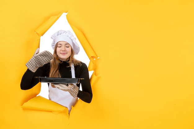 Front view female cook holding black pan on yellow sun time food photo job kitchen emotion cuisine colors