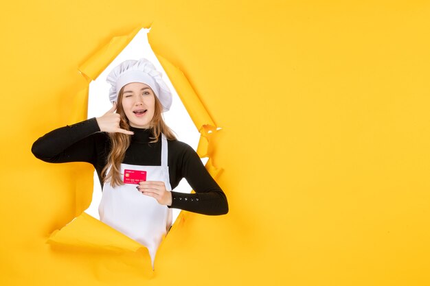 Front view female cook holding red bank card on a yellow job photo emotion food kitchen color money cuisine