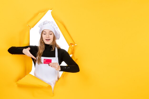 Front view female cook holding red bank card on yellow job photo emotion food kitchen color