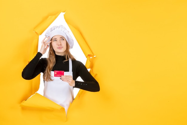 Вид спереди женщина-повар держит красную банковскую карту на желтом фото эмоция еда кухня кухня цветная работа
