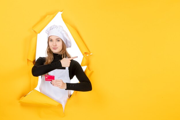 Front view female cook holding red bank card on yellow photo emotion food kitchen cuisine colors money job