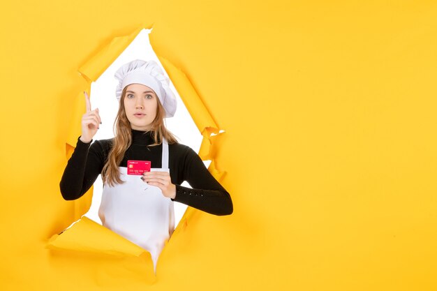 Вид спереди женщина-повар держит красную банковскую карту на желтом фото эмоция еда кухня кухня деньги работа
