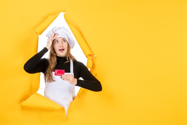 Вид спереди женщина-повар держит красную банковскую карту на желтом фото эмоции деньги кухня кухня цветная работа