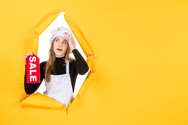 Free photo front view female cook holding red sale writing on yellow color job photo kitchen cuisine emotion