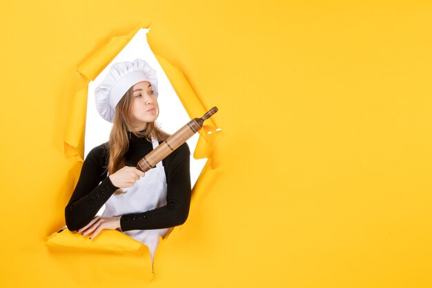 黄色の仕事の料理の食べ物の太陽の写真に麺棒を保持している正面の女性料理人