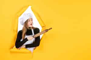 Free photo front view female cook holding rolling pin on yellow color kitchen job cuisine sun photo