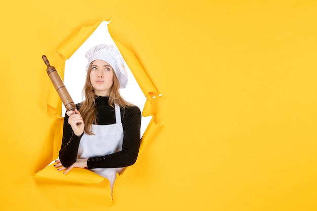 Foto gratuita cuoca di vista frontale che tiene mattarello sulla foto del sole della cucina di colore del lavoro della cucina gialla