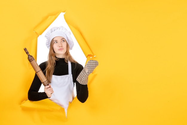 Free photo front view female cook holding rolling pin on yellow photo kitchen job color cuisine food sun