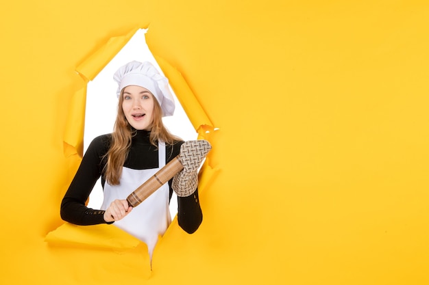 Foto gratuita cuoca vista frontale che tiene mattarello sulla foto gialla cucina lavoro cucina colore sole