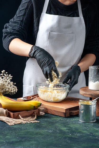 Front view female cook making coconut candies from condensed milk on dark background