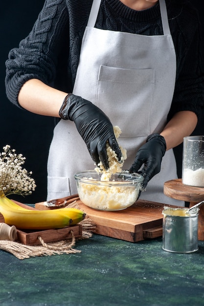 Cuoca vista frontale che produce caramelle al cocco con latte condensato su sfondo scuro