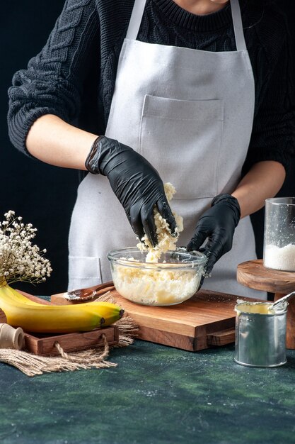 Front view female cook making coconut candies from condensed milk on dark background