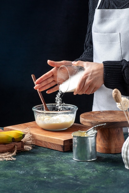 Foto gratuita cuoca vista frontale che versa cocco sul latte condensato su sfondo scuro