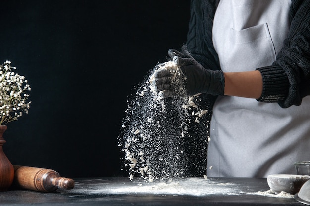 Вид спереди женщина-повар наливает муку на стол для теста на темное тесто яйцо кухня работа пекарня горячее тесто кухня
