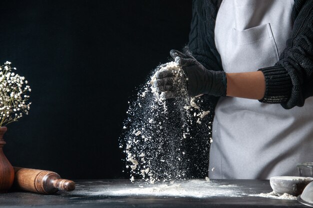 Front view female cook pouring flour on table for dough on a dark dough egg cuisine job bakery hotcake pastry kitchen