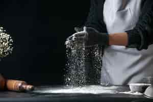 Free photo front view female cook pouring flour on table for dough on dark dough egg cuisine job bakery hotcakes pastry kitchen