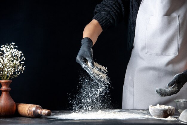 front view female cook pouring flour on table for dough on a dark dough egg job bakery hotcake pastry kitchen cuisine