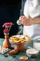 Free photo front view female cook pouring sugar powder on dried pineapple rings on dark fruit cooking job cake pie bakery