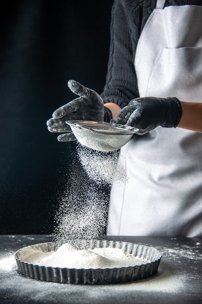 Foto gratuita cuoca vista frontale che versa farina bianca nella padella su torta di uova scure panetteria pasticceria cucina cucina torta hotcake