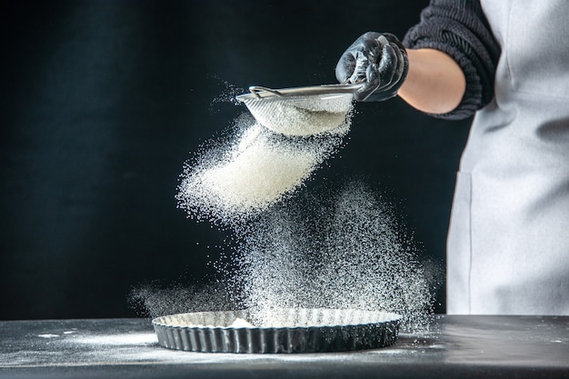 Front view female cook pouring white flour into the pan on a dark egg job bakery hotcake pastry kitchen cuisine dough