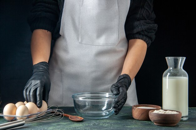 Front view female cook preparing to cook something with milk eggs and flour on dark pastry job cake pies bakery worker cuisine