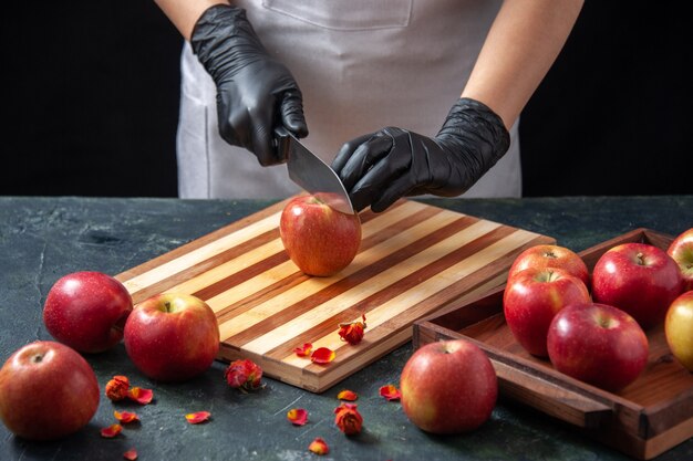 正面図女性料理人は、暗い野菜ダイエットサラダドリンク食品柑橘系フルーツミールエキゾチックでリンゴを切る準備をしています