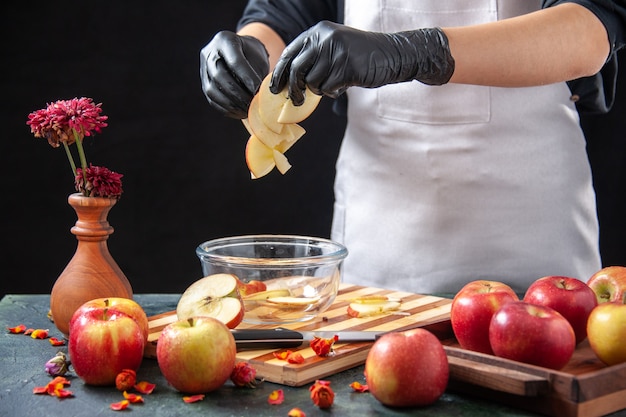 Free photo front view female cook putting sliced apples into plate on dark fruit diet food meal exotic juice work