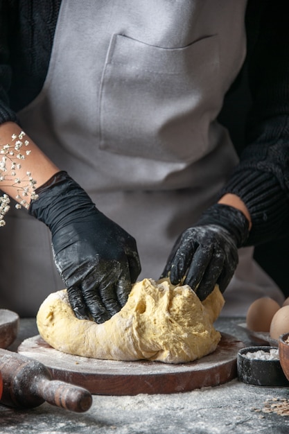 Front view female cook rolling out dough on dark cuisine job pastry hotcake bakery eggs dough
