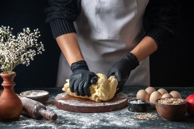 正面図女性料理人が暗い仕事で生地を広げている生の生地ホットケーキベーカリーパイオーブンペストリー