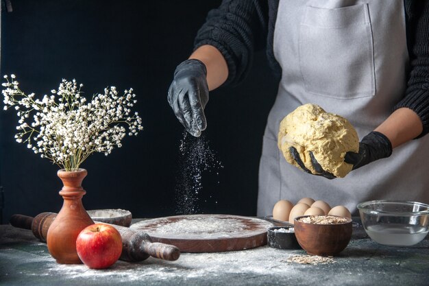 Front view female cook rolling out dough on dark job raw pie oven pastry hotcake bakery egg