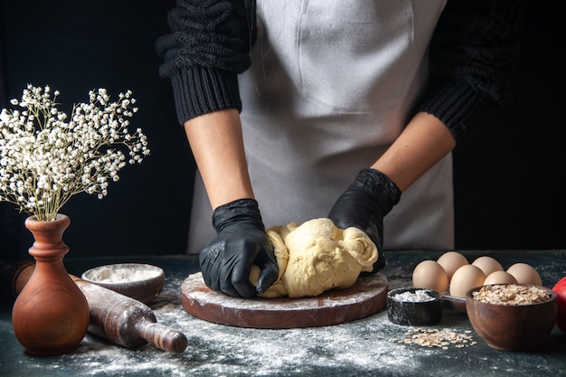 正面図女性料理人が暗いペストリーの仕事で生地を広げている生の生地ホットケーキベーカリーパイオーブン